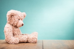 Retro Teddy Bear toy sitting alone front gradient mint green wall background. Vintage instagram style filtered photo