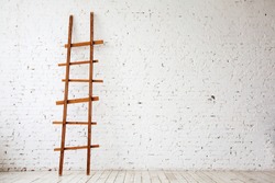 Apartment Renovation. Wooden Ladder near white Brick Wall in empty Room