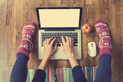 Woman's hands typing on laptop keyboard. Study and work online, freelance, warm socks, winter, home comfort and relax
