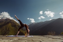 Young flexible woman doing sport yoga exercise brig asana in beautiful mountains landscape on the sunrise