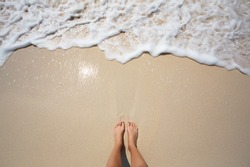Feet on sea beach, wave with sea foam. Summer, heat, sunny day travel, freedom, enjoy and relaxation