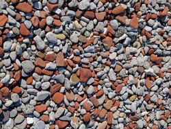 Colorful mixture of pebbles, including red pebbles from broken red bricks eroded by waves