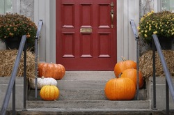 Front door with pumpkins and hay bale for fall or Thanksgiving decorations