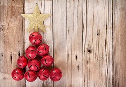 Christmas jingle bells and golden star shaped like a Christmas tree on a rustic wooden plank