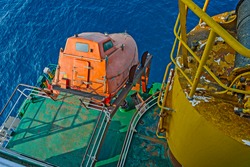 Aft deck of cargo ship with freefall emergency escape orange lifeboat