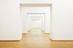 An image of a passageway with wooden floor and white walls