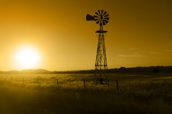 Traditional, old fashioned water pumping ranch windmill, range land, fencing.