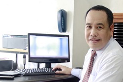 A Filipino executive in his office with business machine around.