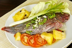 A steam Tialapia fish garnish with fruits and vegetables