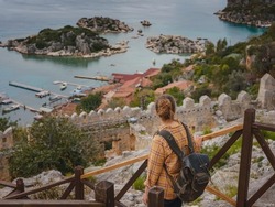 Travel and tourist attractions at Kekova island, Turkey. Woman traveler explores ruins castle of Simena with view of sea bay and Kekova Island with famous flooded city. Tourist attractions in Turkey.