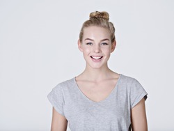 Portrait of a  beautiful young smiling  girl.  Female face with toothy smile. Attractive blond girl poses at studio in a casual grey t shirt 
