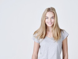 Portrait of a caucasion beautiful young smiling  girl.  Female  with toothy smile. Attractive blond girl poses at studio in a casual t shirt 
