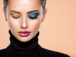 One half face of a beautiful white woman with  bright makeup and the other is natural. Woman portrait with a deep blue eye makeup of one eye. Natural and  vivid make-up on a female face. Fashion style