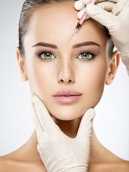 Portrait of young Caucasian woman getting botox cosmetic injection in forehead. Beautiful woman gets botox injection in her face.