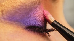 Make-up artist applies makeup to the upper eyelid, close-up.  Makeup artist applies a bright eye shadow with a makeup brush. Tutorial master class of professional makeup. 