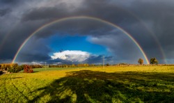 A stunning rainbow against dark clouds over rural fields in Suffolk, UK