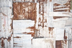 An abstract background image of rusting white corrugated iron sheets overlapping to form a wall or fence.