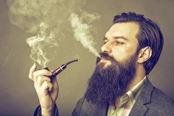 Studio shot of a handsome young man with retro look smoking pipe 