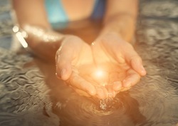 Clear water with glowing light in woman hand