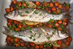 Seabass fish baked with vegetables, herbs and lemon