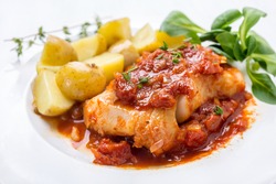 Plate of Cod or Pollack  Fish Fillet Stewed in Tomato and Thyme Sauce Garnished with Boiled New Potatoes