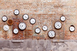 Vintage clock hanging on old brick wall.