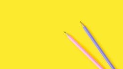 two pencils lie on a bright yellow background, copy space, top view