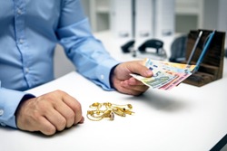 Man buying gold jewellry, pawn shop and euro banknotes