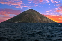 Sunset over Stromboli volcano seen from the boat. Stromboli is one of the eight Aeolian islands and one of three active volcanoes in Italy