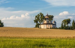 Beautiful 17th century baroque church of Saint Barbara. Building of octagonal shape is standing on the hill in the middle of fields under the setting sun. Procevily village near Breznice  in Czech