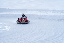 Go karting on icy track in winter. Adult kartng driver in action on outdoor icy track covered with snow