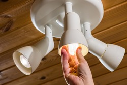A man changes an electric light bulb, energy efficiency
