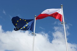 Poland flag and European Union flag on a background of blue sky with clouds.