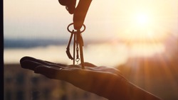 Hand holding three keys over the hand on sunset background, Building concept