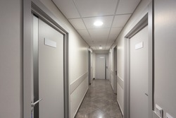 Esthetic and clean modern private clinic or vet hallway corridor with empty posters. White industrial corridor with gray doors