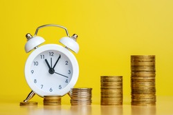 Stacks of coins in row ascending and alarm clock. time is money, efficient business, great income in short time concepts. Copy space for text