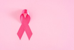 Pink ribbon on pink pastel background, top view with copy space for text. Breast cancer awareness concept