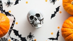 Halloween skull and decorations on white table top view. Flat lay pumpkins, bats, spiders, skull. Halloween greeting card.