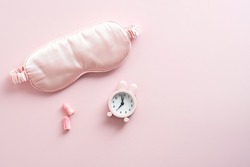 Eye mask, earplugs, pills and alarm clock on pink background. Treatments for Insomnia concept. Flat lay, top view