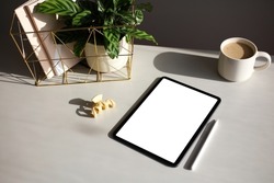 Digital tablet mockup with pen, cup of coffee, green plant, paper notebooks. Elegant women's home office desk table. 
