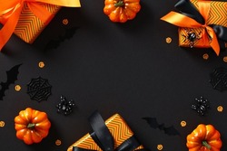 Happy Halloween holiday composition. Frame made of orange gift boxes with ribbon bow, pumpkins, bats, spiders on dark black table. Halloween sale banner design. Flat lay, top view, copy space.