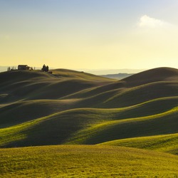 Tuscany, rural landscape in Crete Senesi land. Rolling hills, countryside farm, cypresses trees, green field on warm sunset. Siena, Italy, Europe.