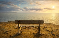Bench in Populonia famous cliff Buca delle Fate at sunset. Elba Island on the horizon. Piombino, Maremma Tuscany, Italy.