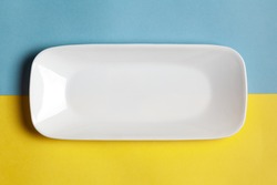 Close-up of an empty ceramic white rectangular or rectangle tray plate for mockup. Over yellow blue background