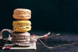 Sweet and colorful macaroon cookies tower on dark background with blank space,selective focus 