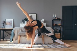 Fit woman trains at home, doing backbend.