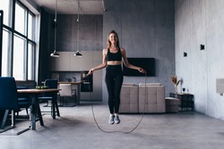 Woman skipping with jump rope at home.
