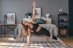 Athletic woman trains at home, stretching and flexibility.