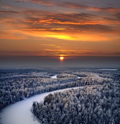 The Aerial view of snow-covered winter forest in time sundown on Christmas Eve.