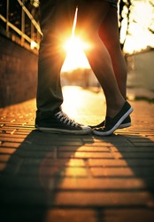 Young couple in love standing on the street in gumshoes in summer sunny warm weather.